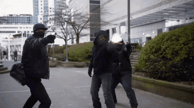 a man wearing a mask is pointing at another man with a gun