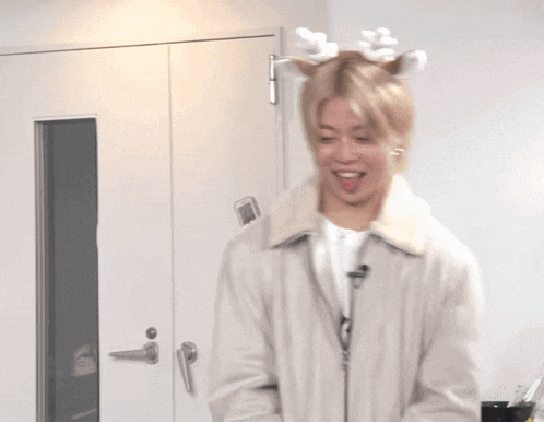 a man wearing a reindeer antlers headband laughs