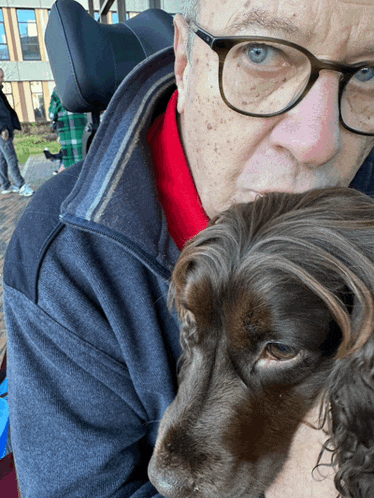 a man in a wheelchair holds a brown dog in his arms