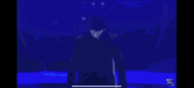 a man in a suit is standing on a stage in front of a blue light .