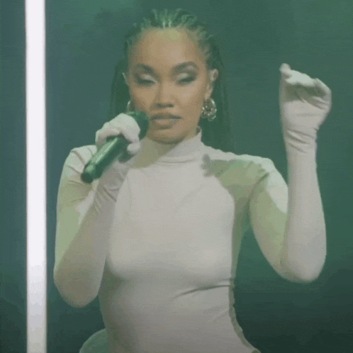a woman is singing into a microphone while wearing gloves