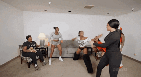 a group of women are dancing in a living room with one wearing a shirt that says " fuck that "