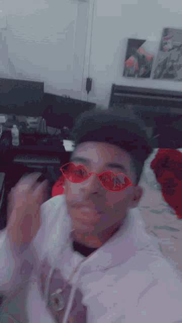 a young man wearing a pair of red sunglasses with hearts on them