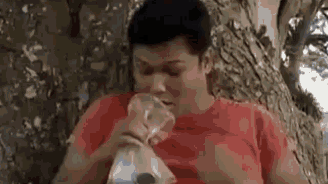 a man is sitting under a tree eating a bag of candy .