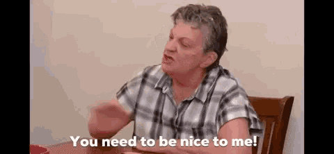 a woman in a plaid shirt is sitting at a table talking to someone .