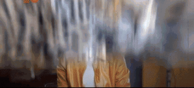a blurry picture of a man wearing a yellow jacket and tie .