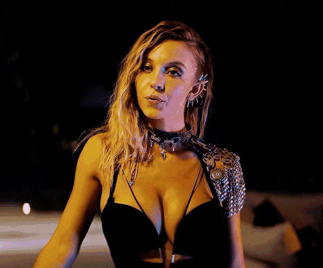 a woman in a very revealing black top with chains on her shoulder