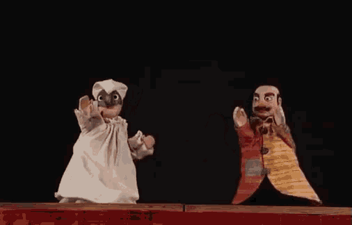 a couple of puppets on a stage with one wearing a white dress