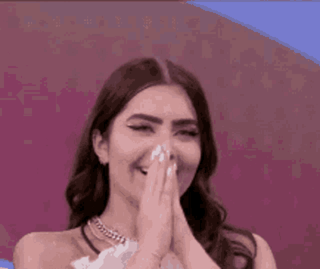 a woman in a white dress is covering her face with her hands .