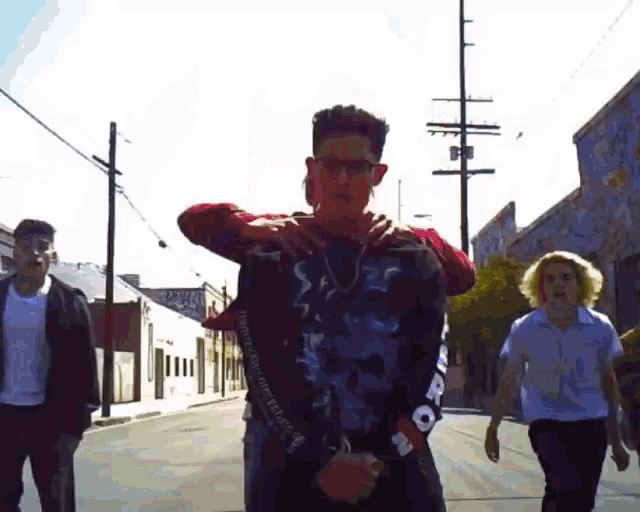 a group of young men are walking down a street and one of them is wearing a shirt that says ' supreme '