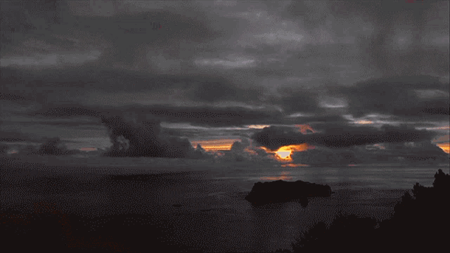 a sunset over a body of water with a small island in the foreground