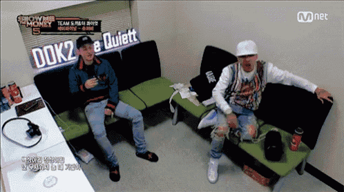 two men sit on a couch in a room with a sign that says dok2