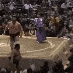 a group of men are wrestling in a sumo ring .