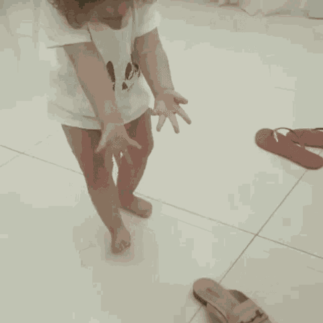 a little girl is standing on a tiled floor .