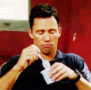 a man is eating ice cream with a spoon while sitting in front of a red wall