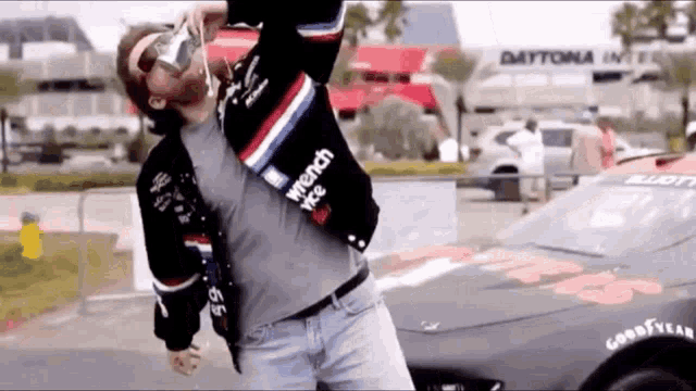 a man in a wrench race jacket drinking from a can