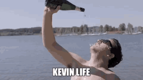 a shirtless man is pouring champagne into his mouth while standing in the water .