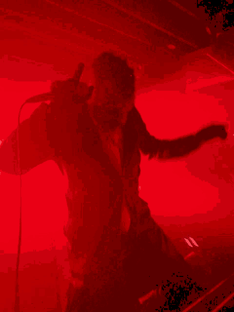 a person is standing in a dark room with a red background