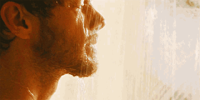 a close up of a man taking a shower with water pouring on his face