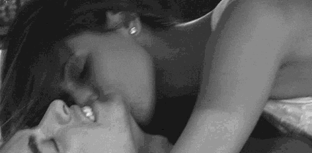 a black and white photo of a woman kissing a man on the cheek .
