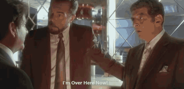a man in a suit and tie is saying " i 'm over here now "
