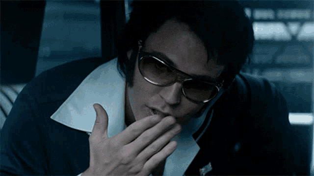a man wearing sunglasses is covering his mouth