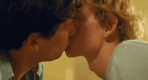 a close up of two men kissing each other on the nose .