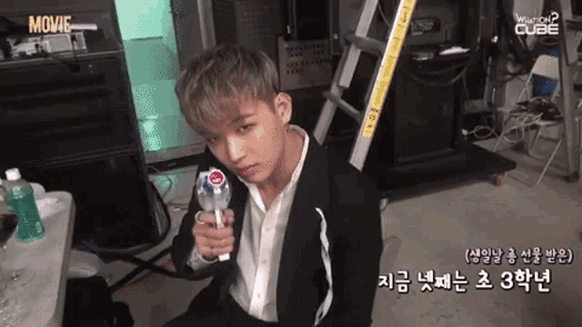 a young man in a suit is holding a lollipop and the words movie cube are visible on the bottom