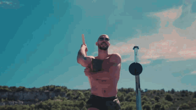 a man without a shirt is holding a stick in front of a blue sky