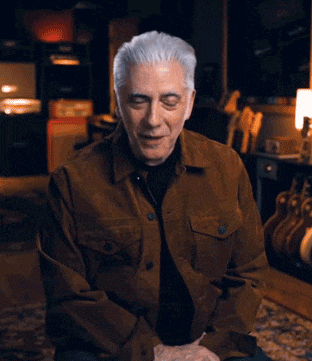 a man in a brown jacket waving his hand