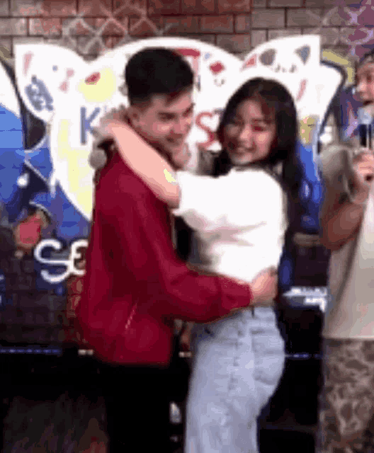 a man and a woman are hugging each other in front of a graffiti wall .