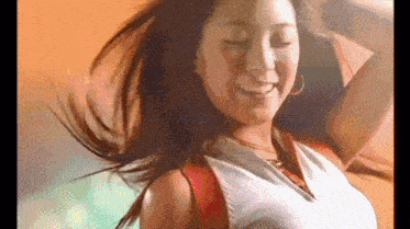 a woman is dancing with her hair blowing in the wind and smiling .