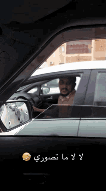 a man is driving a car with arabic writing on it