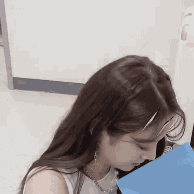 a close up of a woman 's face with a blue folder in her hand .