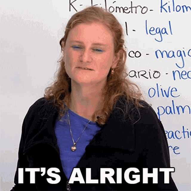 a woman standing in front of a white board with the words it 's alright written on it