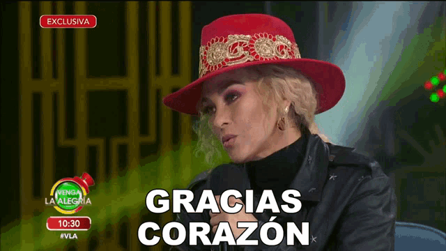 a woman wearing a red hat says gracias corazon on a television screen