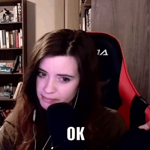a woman is sitting in a chair with a microphone in front of her and the word ok is on her face .