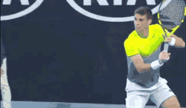 a man in a yellow shirt is holding a tennis racquet on a court