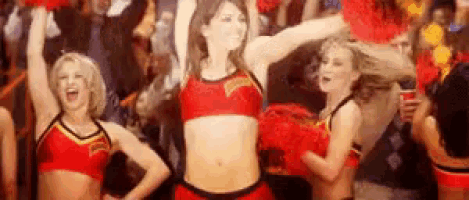 a group of cheerleaders are dancing in front of a crowd at a basketball game .