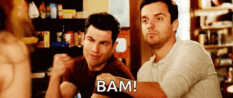 two men are sitting at a table with their fists in the air and one of them is shouting bam .