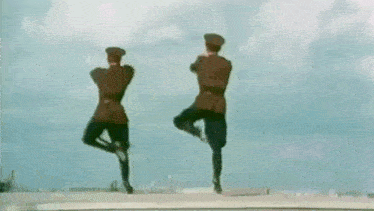 two men in military uniforms are dancing together on a field .