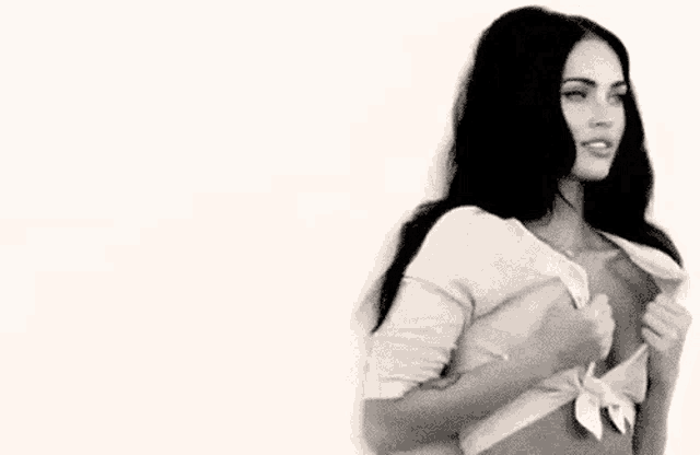 a woman in a white shirt is taking off her shirt .