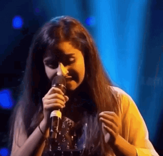 a young girl is singing into a microphone on stage .