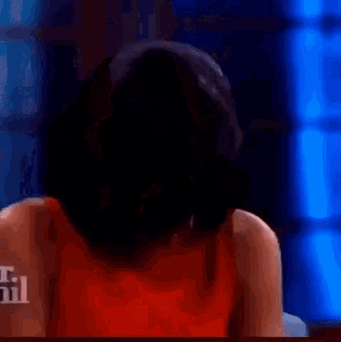 a woman in a red dress is smiling while touching her hair .