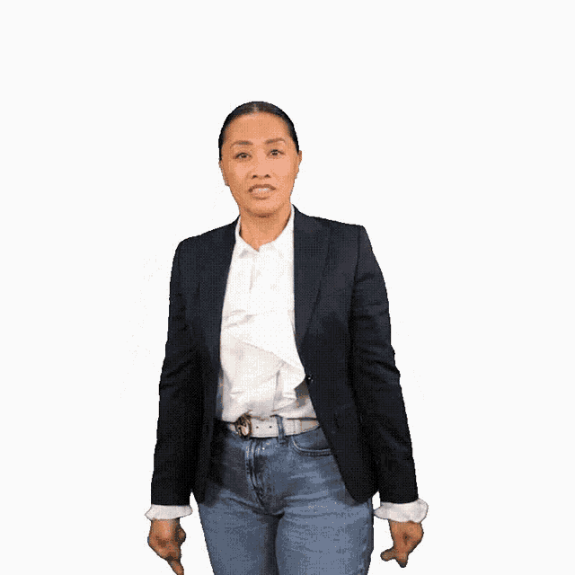 a woman in a black jacket and blue jeans is giving the middle finger .