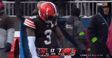 a football player with the number 3 on his jersey stands on the sidelines