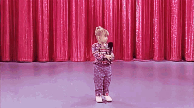 a little girl is holding a microphone on a stage