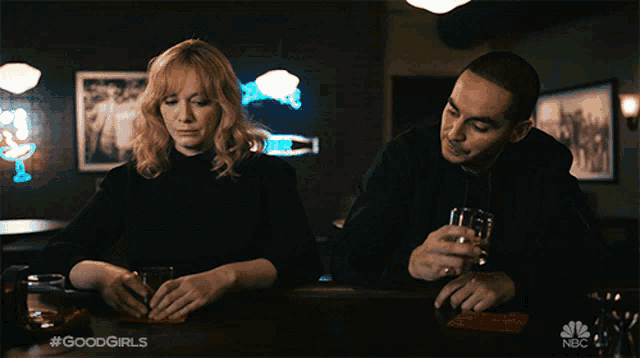 a man and a woman are sitting at a bar with the hashtag #goodgirls