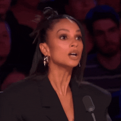 a woman is speaking into a microphone and making a surprised face