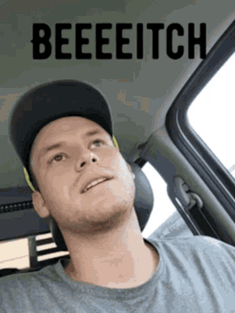 a man wearing a hat is sitting in a car with the words beeeeitch above his head